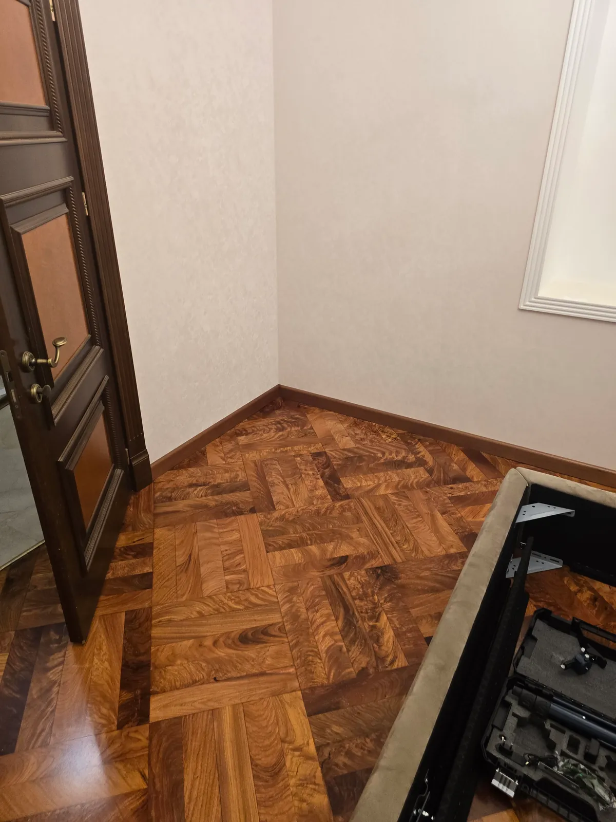 Комната с художественным паркетом-ёлочкой и деревянным плинтусом по периметру, классическая дверь в проёме